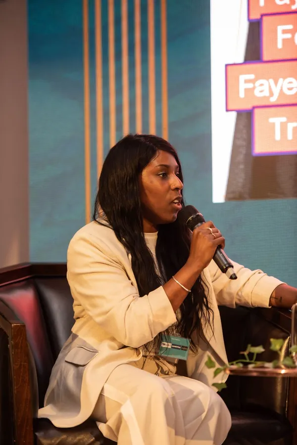 Faye speaking into a microphone on stage at the Athena Effect