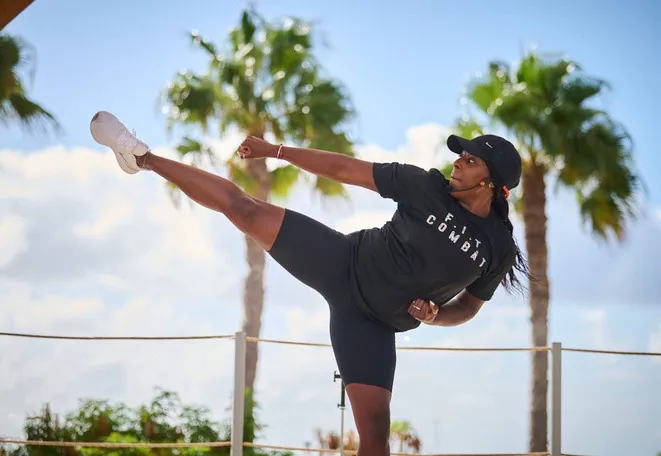 Faye throwing a high kick on a sunny terrace lined with palm trees