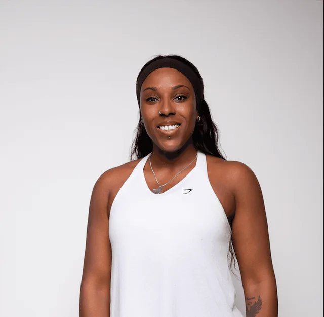 Faye smiling in a white training vest and headband