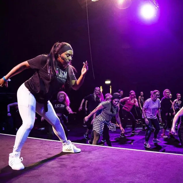 Faye leading a packed F.I.T Jam class on stage under purple lights